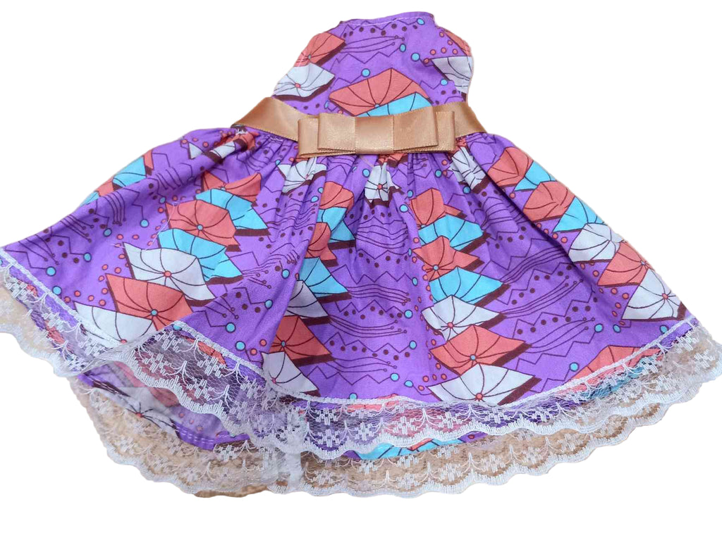 A traditional Haitian purple dress with a floral pattern and lace details, designed for use with dolls.